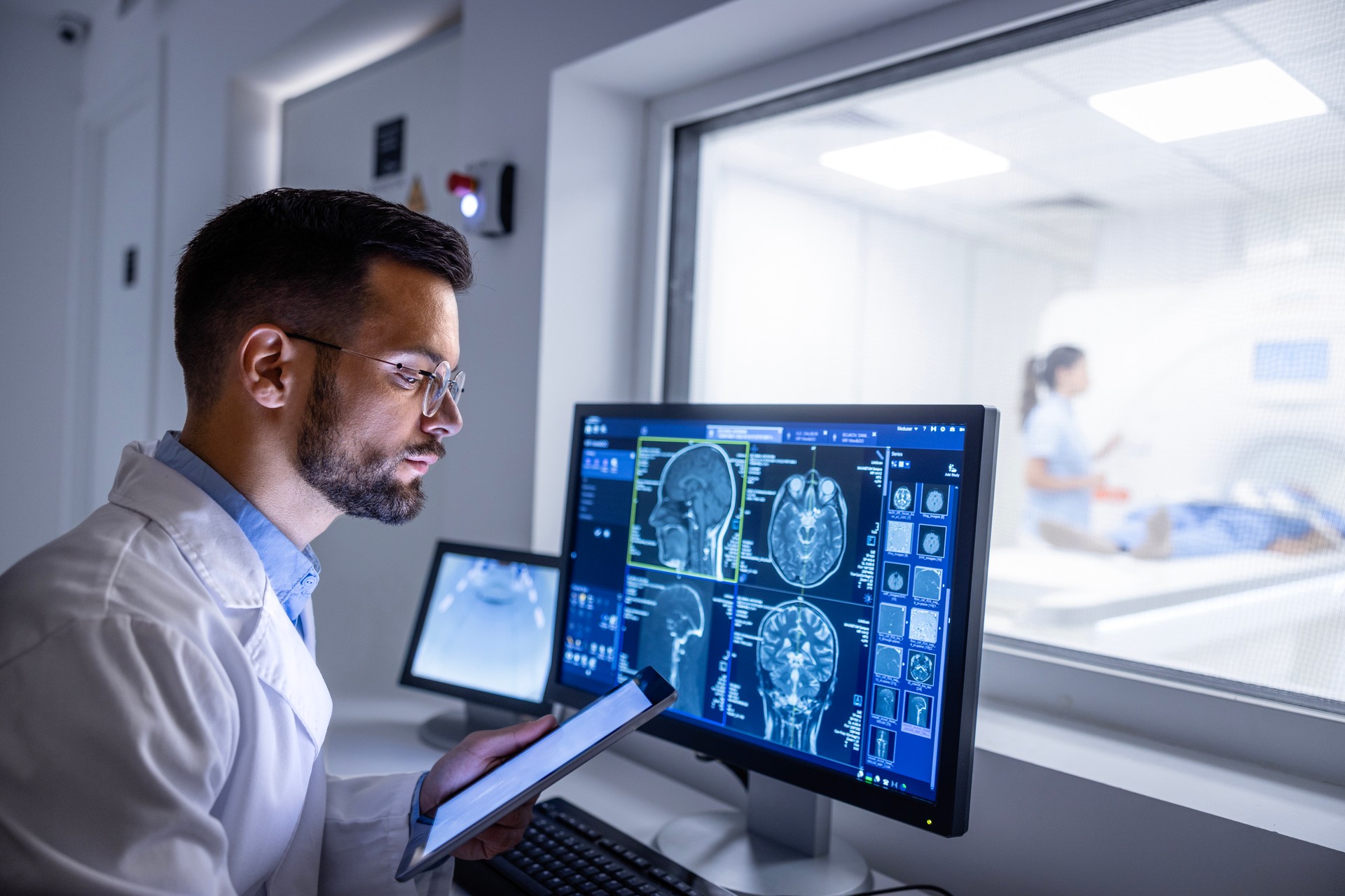 Doctor examining X-ray images in MRI control room.